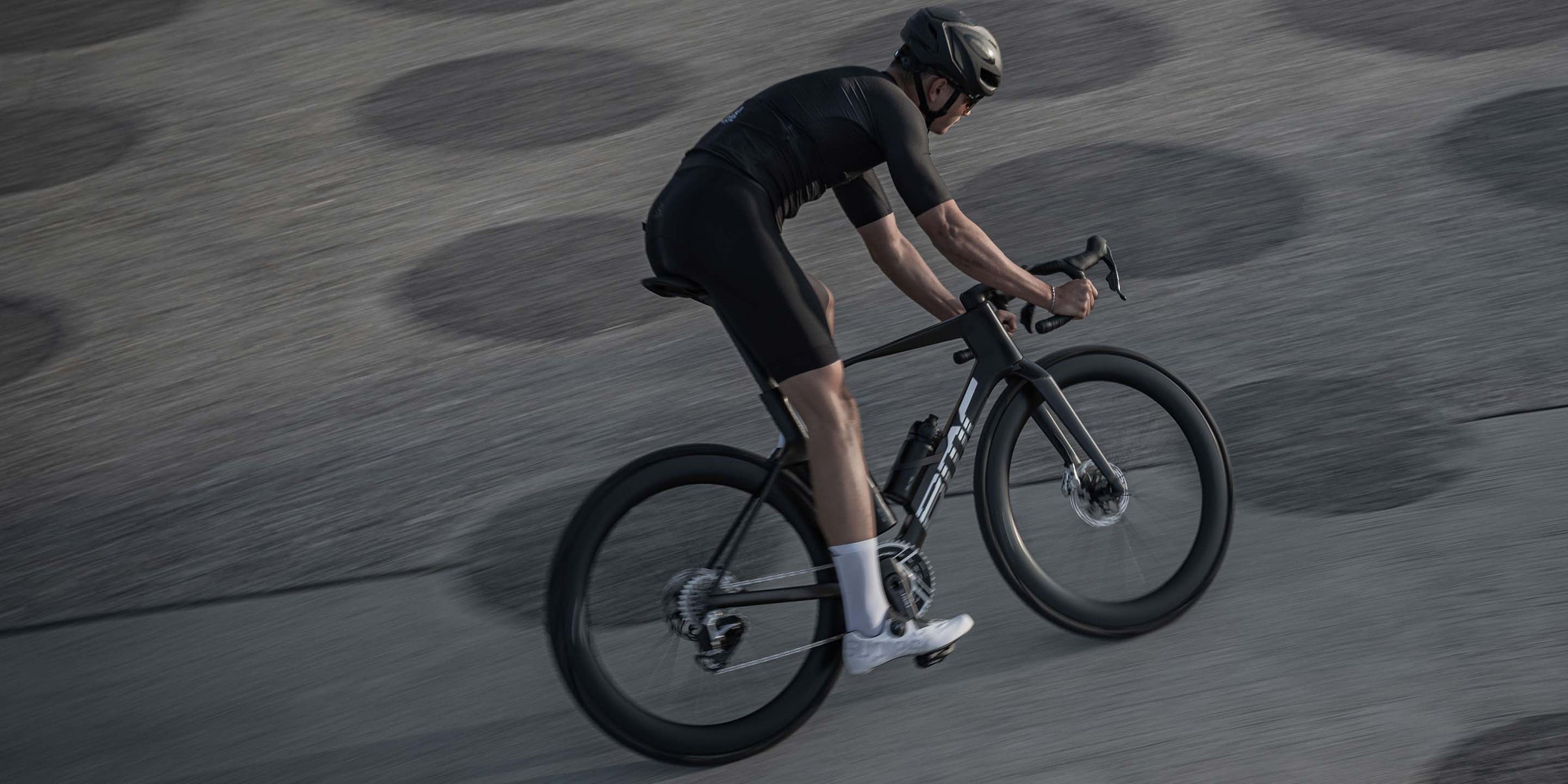 Road biker on the road with black carbon racing bike Teammachine R Mpc from BMC